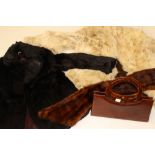 A black rabbit fur coat; together with a cream rabbit fur coat, pair of gloves,