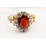 A garnet and diamond oval cluster 9ct gold dress ring, size 'R', 5.