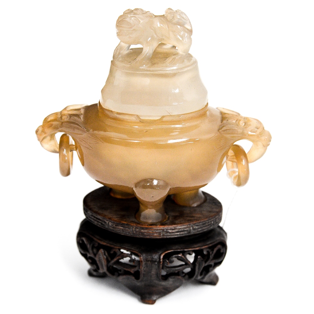 A Chinese amber jade or agate censer on hardwood stand, ring handles, the lid with a Shi finial,