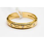 An 18ct gold and diamond wedding band, three gypsy set diamond chips, approx 3.