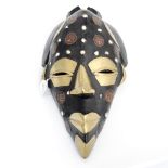 An African modern stylised wall mask with brass and coin decoration.