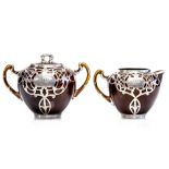 An Art Nouveau silver overlaid brown glazed milk jug and matching sugar pot, circa 1905,