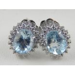 A pair of 18 cart white gold, diamond, and aquamarine cluster earrings, the aquamarines of 2.78