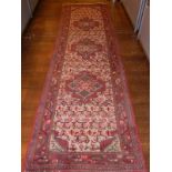 A Caucasian ivory ground runner with triple central lozenge medallion within a floral field and