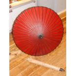 Two Oriental parasols, having paper covers and wooden ferrules and handles.