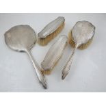 A silver backed dressing table set, comprising a hand mirror, hair brush, and two clothes brushes,