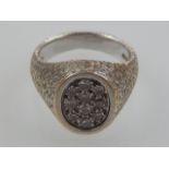 An 18ct white gold diamond cluster ring with oval mount and bark effect shoulder and band.