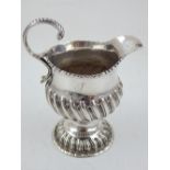 A George III embossed silver cream jug with C scroll handle and wrythen fluted body marks rubbed,