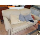 A Victorian style two seater sofa, upholstered in studded natural fabric, on square tapered feet.