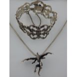 A silver pendant in the form of a winged demon, on white metal chain,