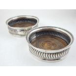 A pair of George III silver wine coasters, gadrooned with mahogany bases, D. 15cm, (2)