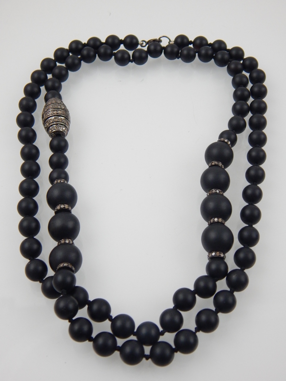 A designer single strand black hardstone necklace, possibly obsidion, the two size stones divided by