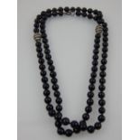 A designer single strand black bead necklace the faceted stones divided by two enamelled white metal