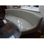 A contemporary sofa, crescent shaped and upholstered in grey fabric, the seat raised on a bronzed