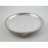 A George III circular silver card tray, with gadrooned border on three cast lions paw and scroll