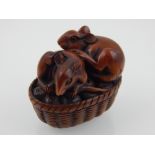 A Japanese carved boxwood netsuke modelled as two mice on an oval wicker basket W 4.5 cms