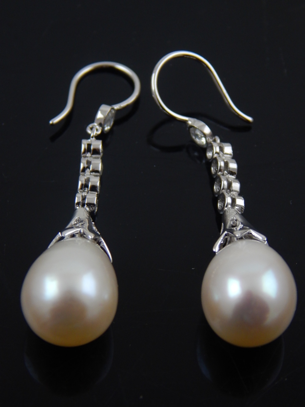 A pair of white gold, diamond, and pearl drop earrings.