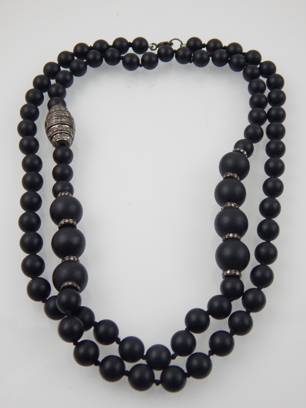 A designer single strand black hardstone necklace, possibly obsidion, the two size stones divided by - Image 3 of 3