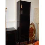 A contemporary oriental black lacquer tall cupboard, the door enclosing a shelved interior above two