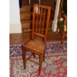 An early 19th century mahogany correction chair with triple vertical rail back and solid seat on