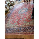 A Kashan rug, with a blue medallion on a red foliate ground within a blue foliate border, 414 x