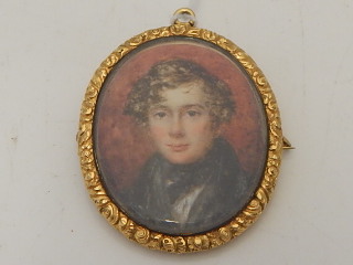 A 19th century yellow metal mounted pendant brooch, set portrait miniature, depicting a young