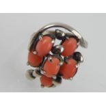 A coral set dress ring, with an asymmetrical arrangement of six cabochon cut stones, 4.6g.