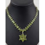 A silver and peridot necklace claw set circular faceted stones with central flowerhead drop.