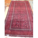 A Baluch rug, with a black geometric patter on a madder ground, 254 x 150cm.