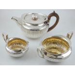 A Georgian three piece silver tea set, with gadrooned design and having gilt washed interior,