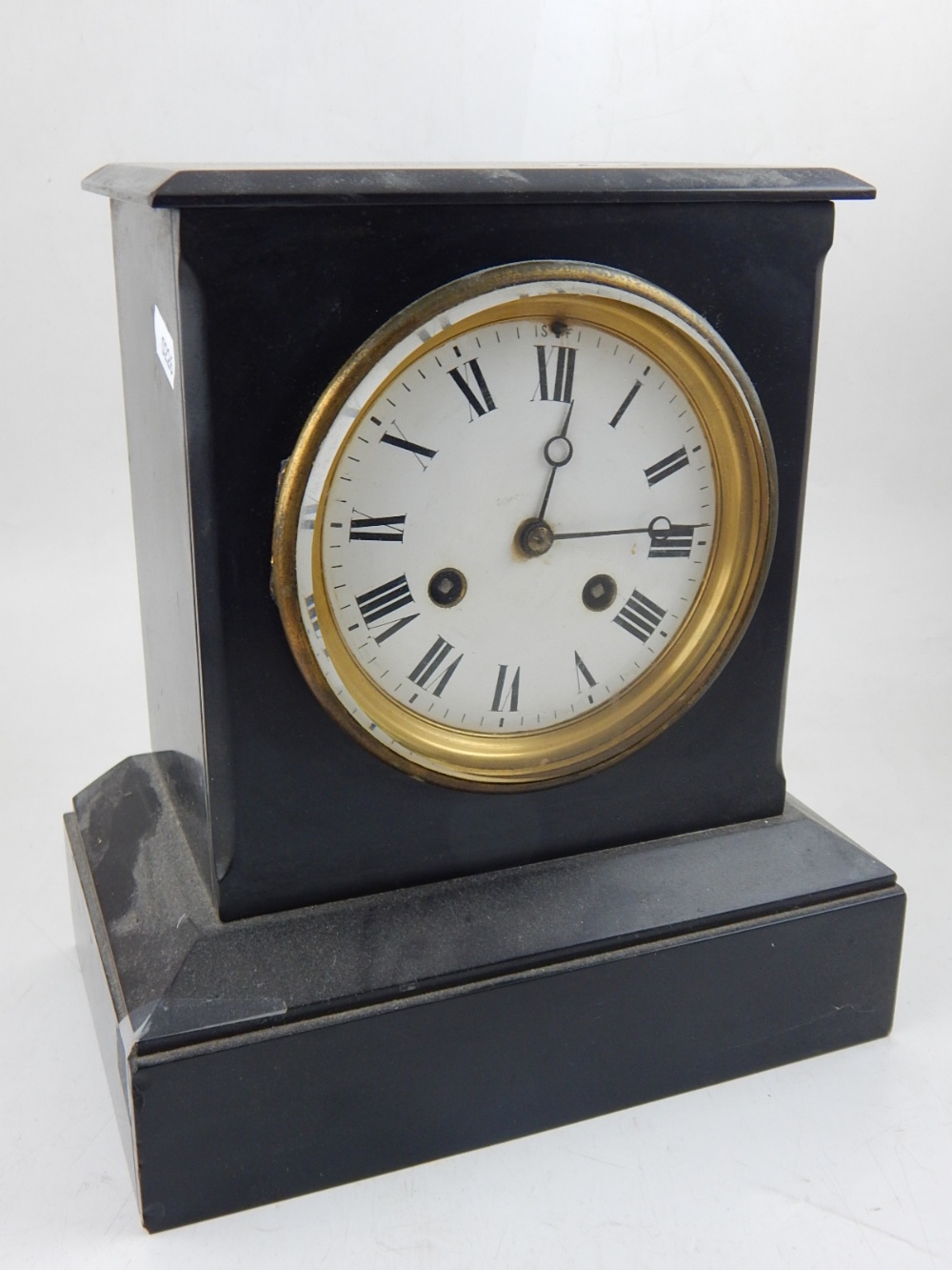 A late Victorian black slate mantel clock, the white enamel dial set out with Roman numerals,