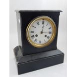 A late Victorian black slate mantel clock, the white enamel dial set out with Roman numerals,