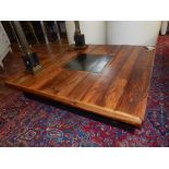 An eastern square hardwood low table with central faux iron panel, on block feet. L.