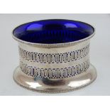 An early 20th century silver dish ring, with pierced circular body and blue glass liner,