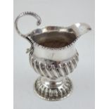 A George III embossed silver cream jug with C-scroll handle and wrythen fluted body marks rubbed,