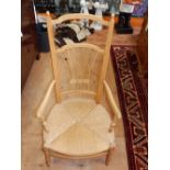 An early 20th century American beech rush seat elbow chair with ribbon tied wheatear splat on