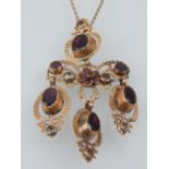 A Victorian yellow metal, garnet and white stone pendant necklace of filigree form,