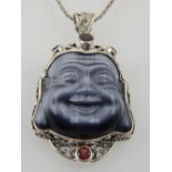 A white metal mounted moonstone pendant, in the form of Buddhas head, with garnet decoration,