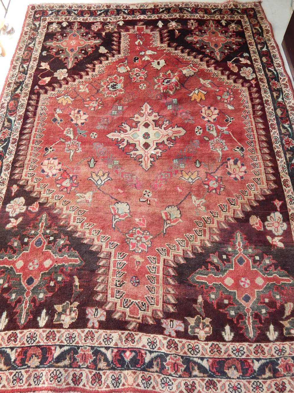 A red groudn Persian rug, with geometric design to centre, within stepped and floral border,