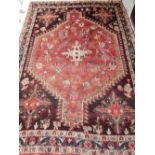 A red groudn Persian rug, with geometric design to centre, within stepped and floral border,