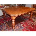 An Edwardian walnut extending dining table, the top with cusped corners and one leaf insertion, on