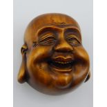 A Japanese carved boxwood netsuke modelled as a laughing Buddha head, bears character mark. L. 4cm