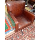 An Aviator swivel chair, upholstered in brown leather, with riveted aluminium back and side