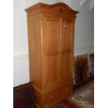 A modern pine wardrobe the carved arched pediment over two panelled doors and base drawer. W. 106cm