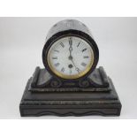 A late Victorian black slate mantel timepiece, of drum form, with a white enamel dial set out with