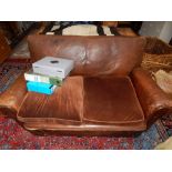 A vintage two set sofa, upholstered in dark tan leather with brown velvet cushions, W. 140cm.