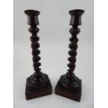 A pair of early 20th century walnut candlesticks, the barley-twist support on a square base, H.18cm,