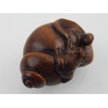 A Japanese carved boxwood netsuke modelled as a toad and tortoise in and upon a conch shell, bears