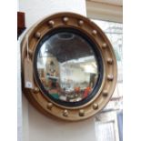 A Regency style convex wall mirror, the ball mounted frame incorporating a reeded ebonised slip