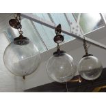 Three clear glass globe hanging lamp, decorated with a fine web of brass wire,